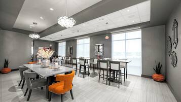 A modern dining area with a large table, chairs, and pendant lighting.