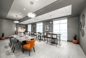 Een moderne eethoek met een grote tafel, stoelen en hanglampen.