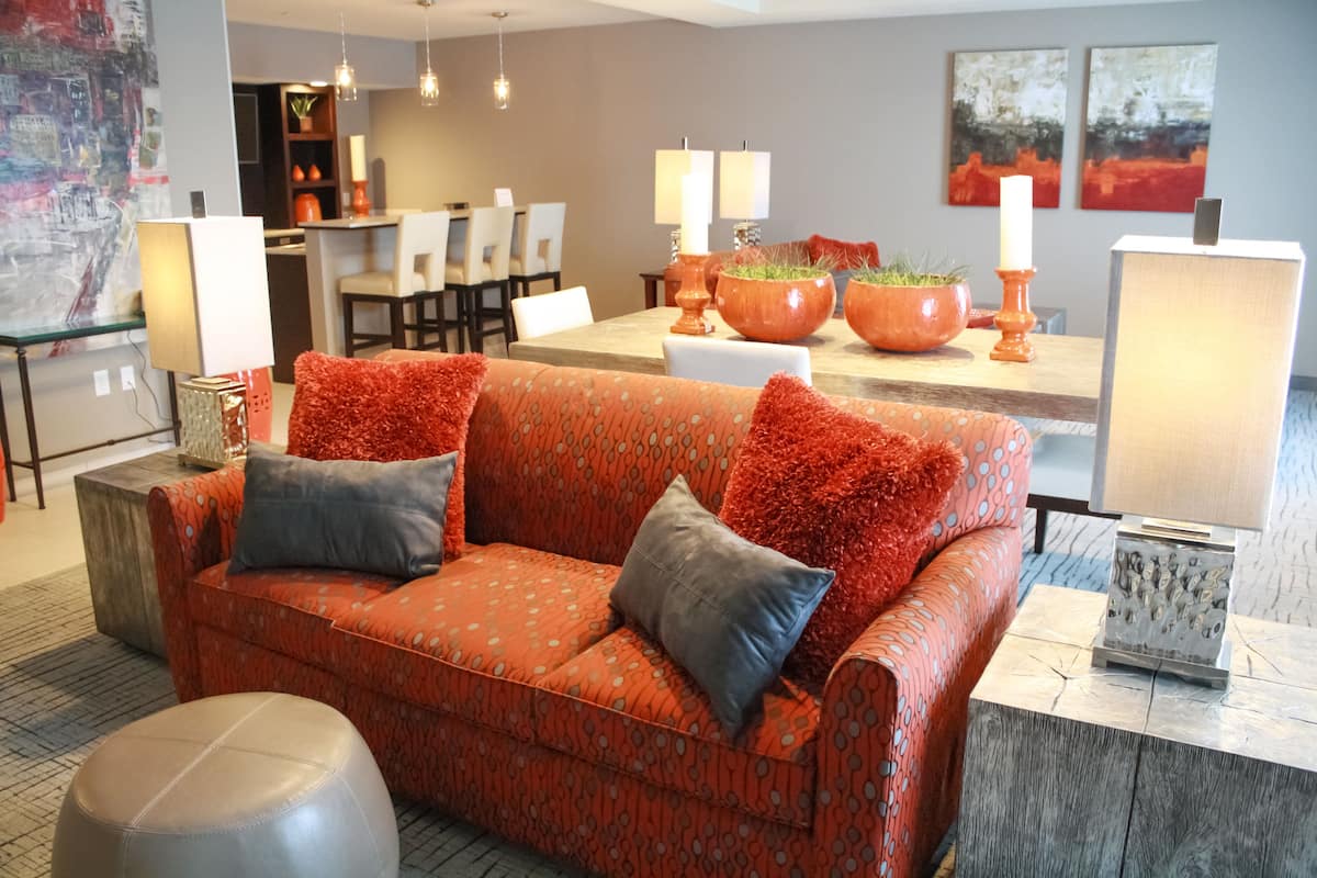 Ein Wohnzimmer mit einem gemusterten Sofa, einem Hocker und einem Essbereich mit Tisch und Stühlen.