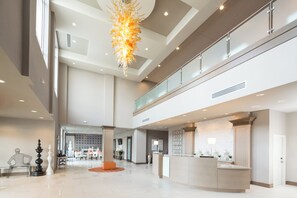 Un hall d’entrée spacieux, doté d’un comptoir de réception, d’un grand lustre et d’un plafond haut.