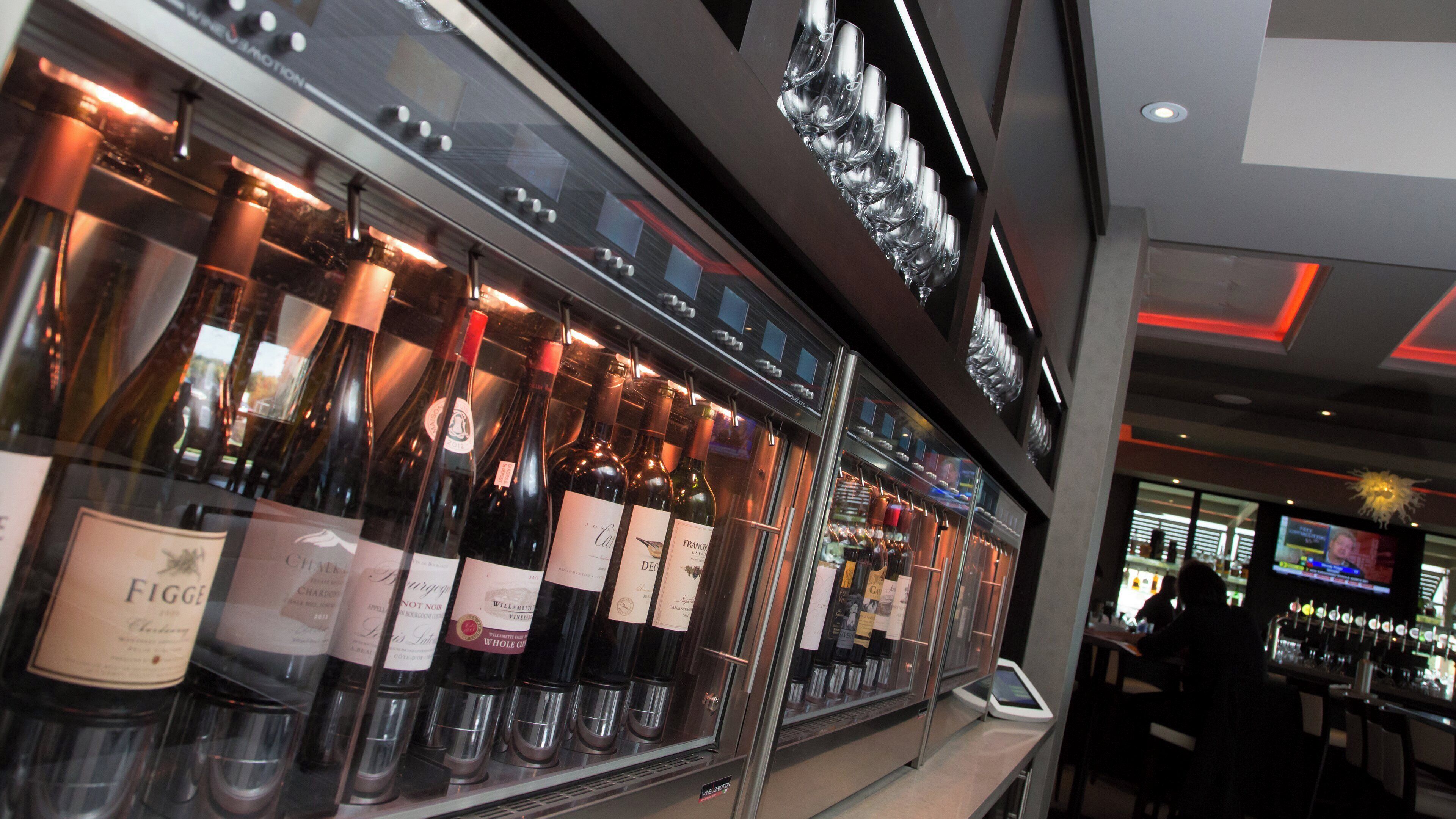 A wine display with bottles and glasses, a digital screen, and a bar area.