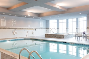 Une piscine intérieure avec des règles d’utilisation claires et un panneau indiquant la présence d’un sauveteur.