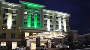Un hotel de varios pisos con una entrada destacada y un área techada al frente.