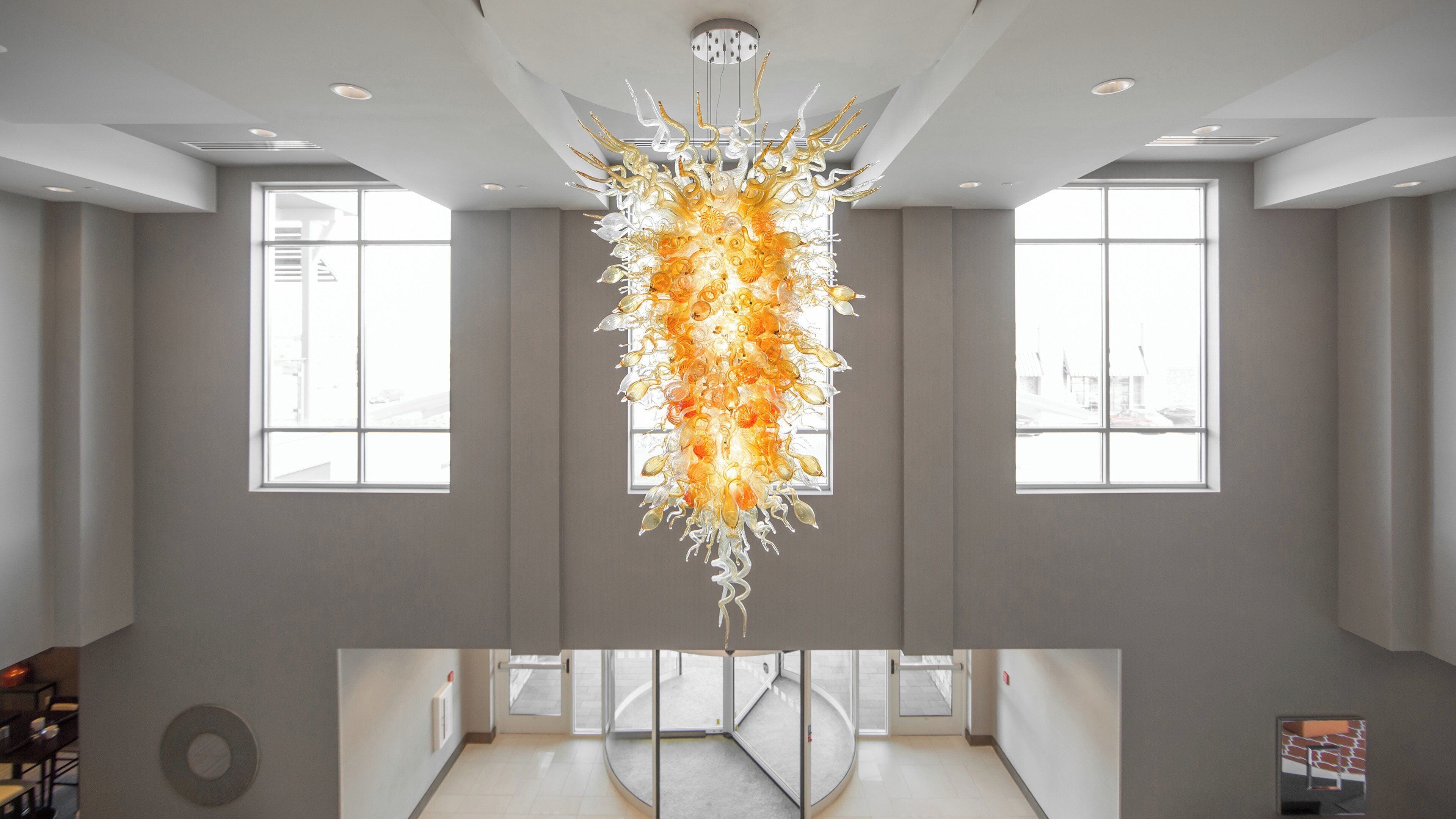 A spacious interior with a central chandelier, large windows, and a circular floor plan.