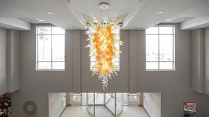 Een ruim interieur met een centrale kroonluchter, grote ramen en een ronde indeling.