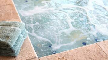 A hot tub with visible bubbles, a tiled edge, and a stack of towels.