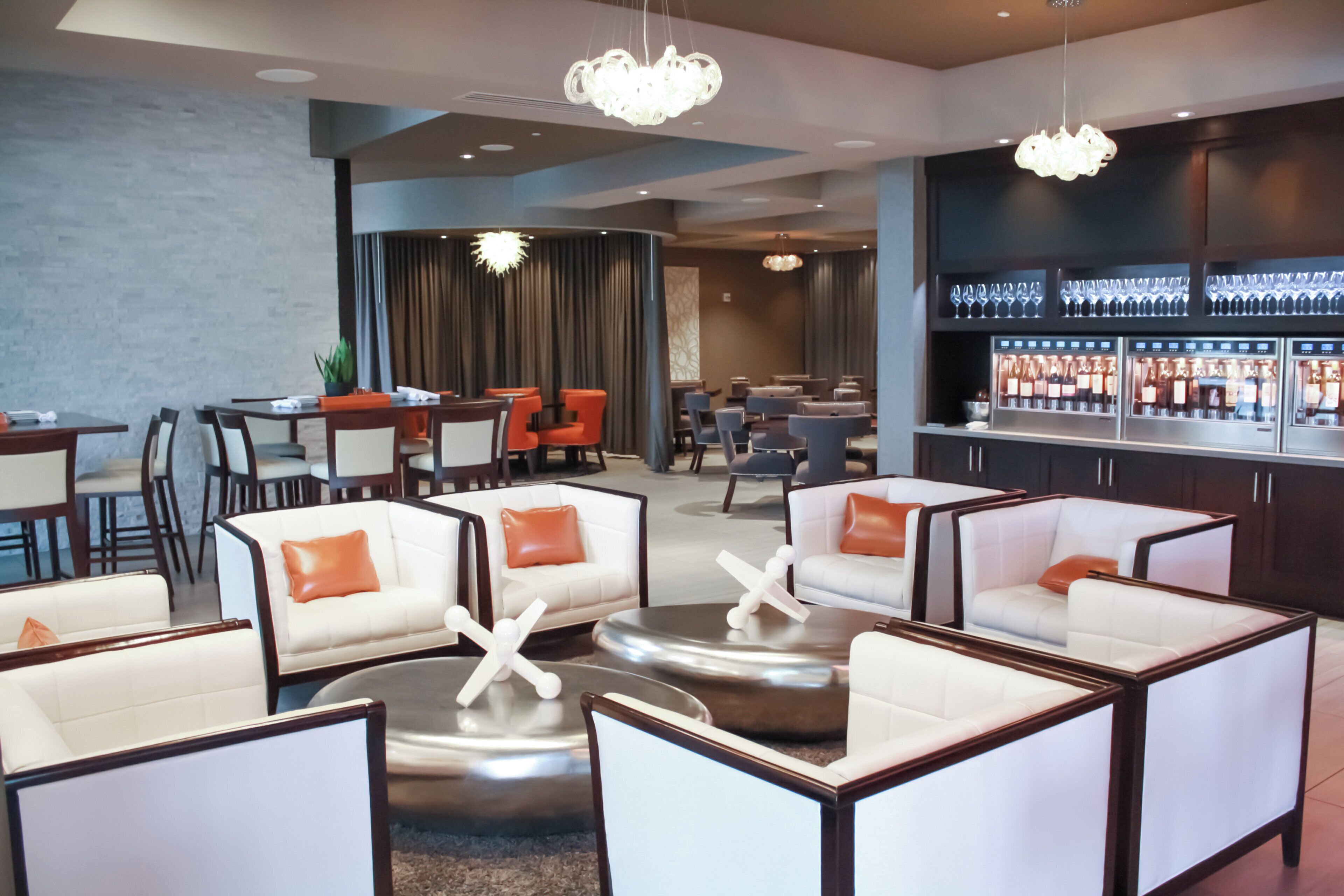 A modern lounge area with seating arrangements, a bar, and a dining area.
