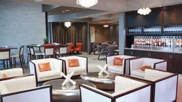 A modern lounge area with seating arrangements, a bar, and a dining area.