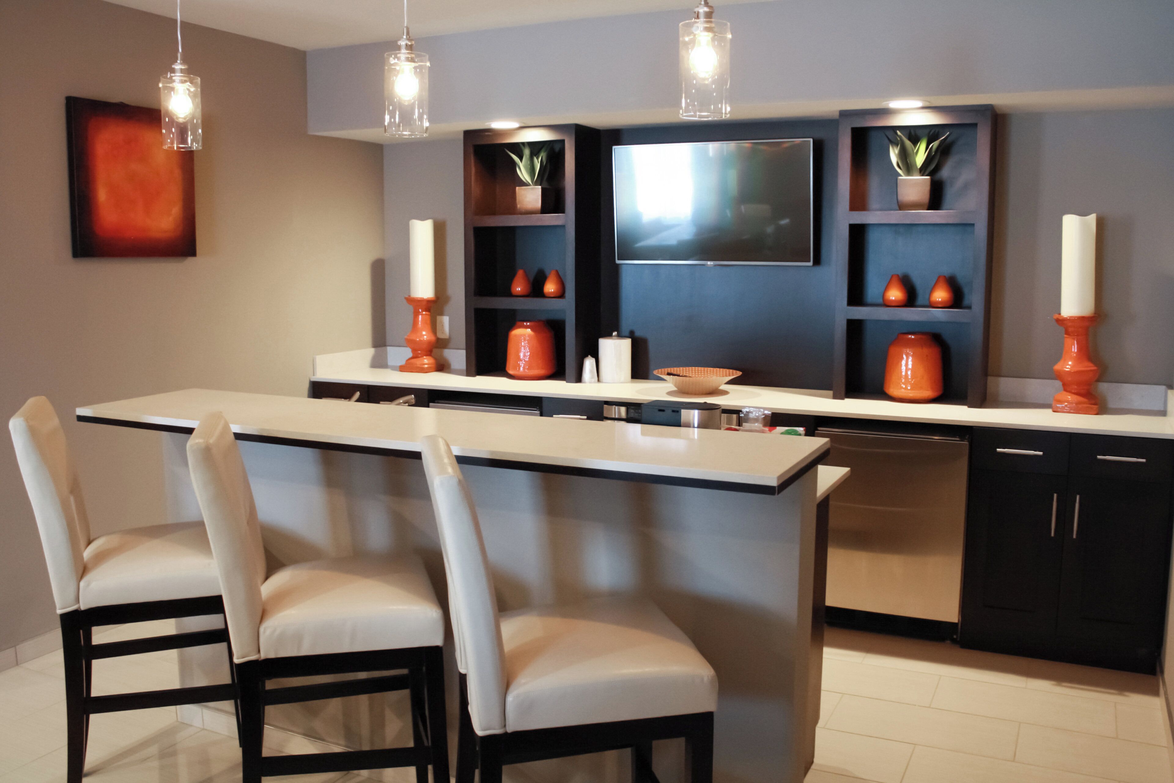 Una cocina moderna con una isla central, taburetes de bar, lavavajillas y jarrones decorativos.