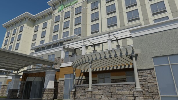 A Holiday Inn hotel with a stone facade, multiple windows, and a covered entrance area. - Holiday Inn Hotel & Suites Davenport by IHG (Davenport)