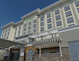 Un hotel Holiday Inn con fachada de piedra, múltiples ventanas y un área de entrada cubierta.