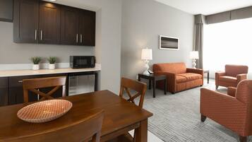 Quarto de hotel moderno com área de refeições, cozinha compacta e espaço para sentar.
