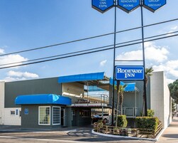 Un Rodeway Inn con un toldo azul, zona de estacionamiento techada y un letrero que indica servicios cercanos como CNN, ESPN y descuentos para grupos.
