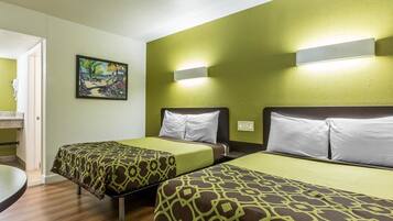 Una habitación de hotel con dos camas, un cuadro en la pared y un baño visible a través de una puerta abierta.