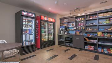 Een ruimte met een snackautomaat, een magnetron en planken vol snacks en drankjes.