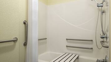 A bathroom with a bathtub, shower, and grab bars.
