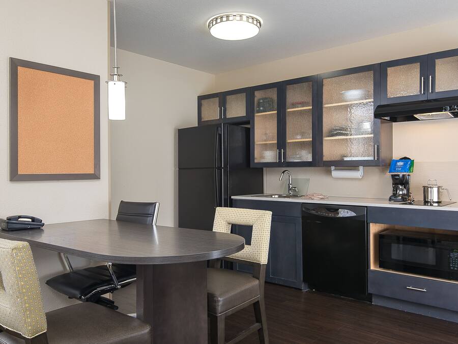 A compact kitchen with a dining area, featuring dark cabinetry, a built-in microwave, and a small coffee maker.