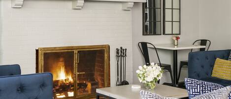 A cozy living room with a fireplace, comfortable seating, and a dining area.
