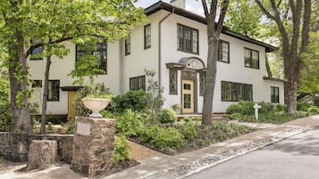 A two-story house with a stone foundation, a front porch, and a well-maintained garden.
