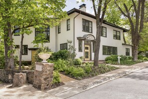 A two-story house with a stone foundation, a front porch, and a well-maintained garden.