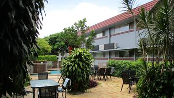 A courtyard with a pool, outdoor seating, and a building with a red roof.