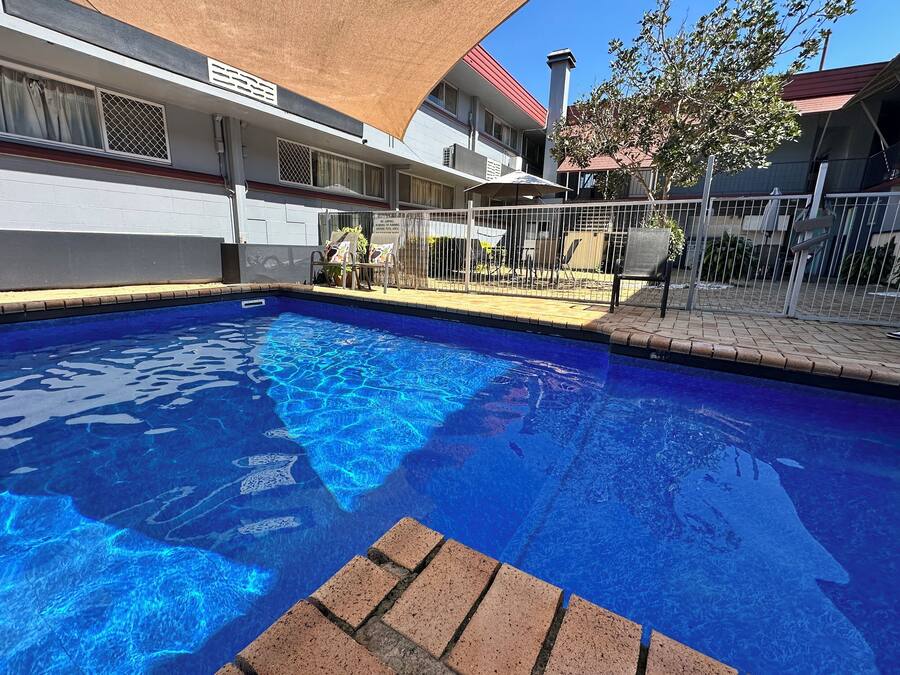 Una piscina al aire libre, sombrillas, sillones reclinables de piscina
