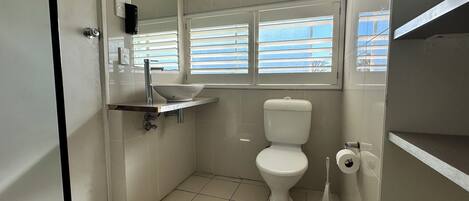 Baño pequeño con inodoro, lavamanos y ventana.