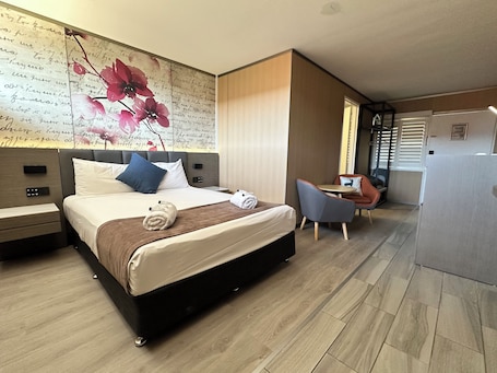 A modern hotel room with a large bed, bedside tables, a desk, and a chair.