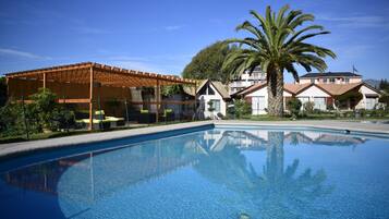 Una piscina al aire libre, sillones reclinables de piscina
