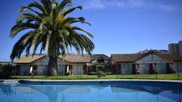 Una piscina al aire libre, sillones reclinables de piscina