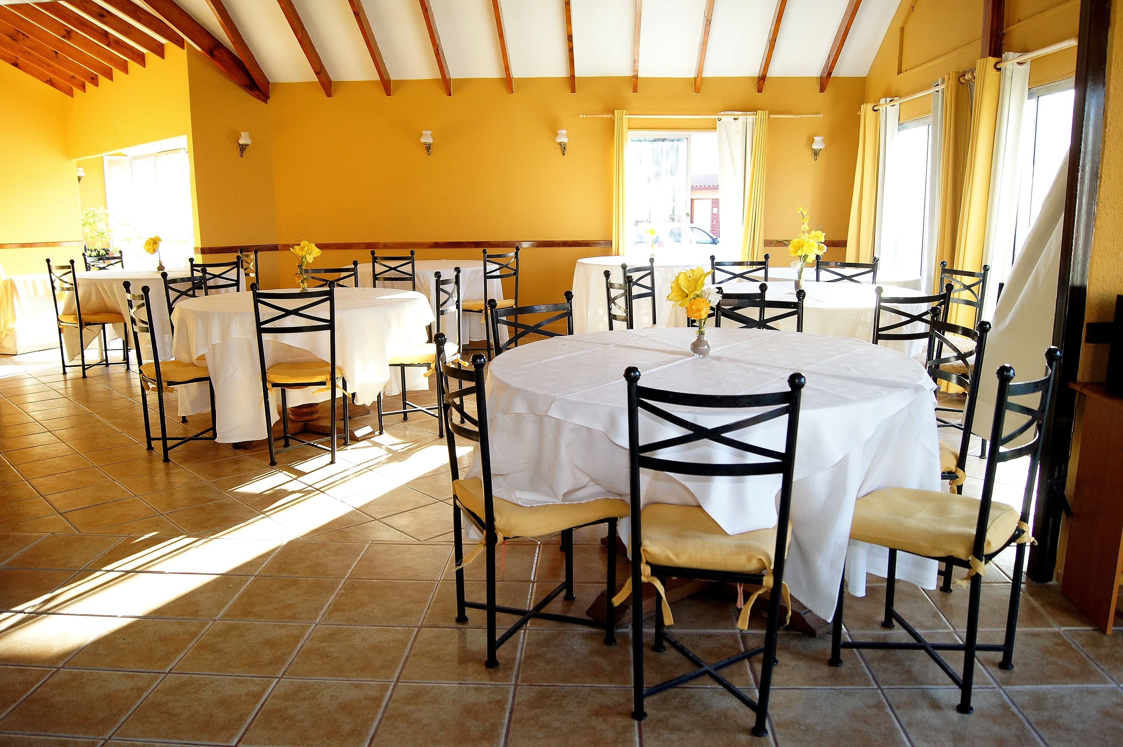 A dining area with round tables, chairs, and yellow flowers.