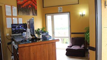 A reception area with a wooden desk, computer monitors, and a plant.