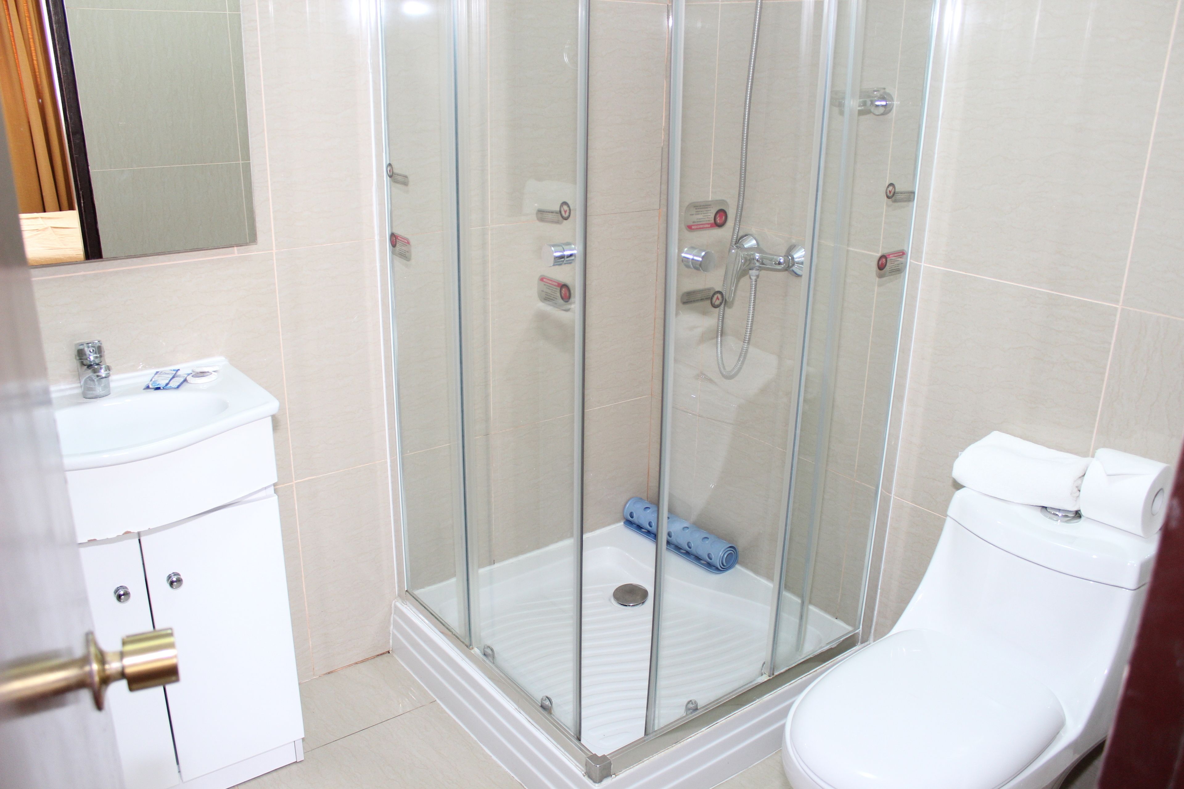 Un bany amb dutxa tancada amb vidre, un lavabo blanc i un vàter.