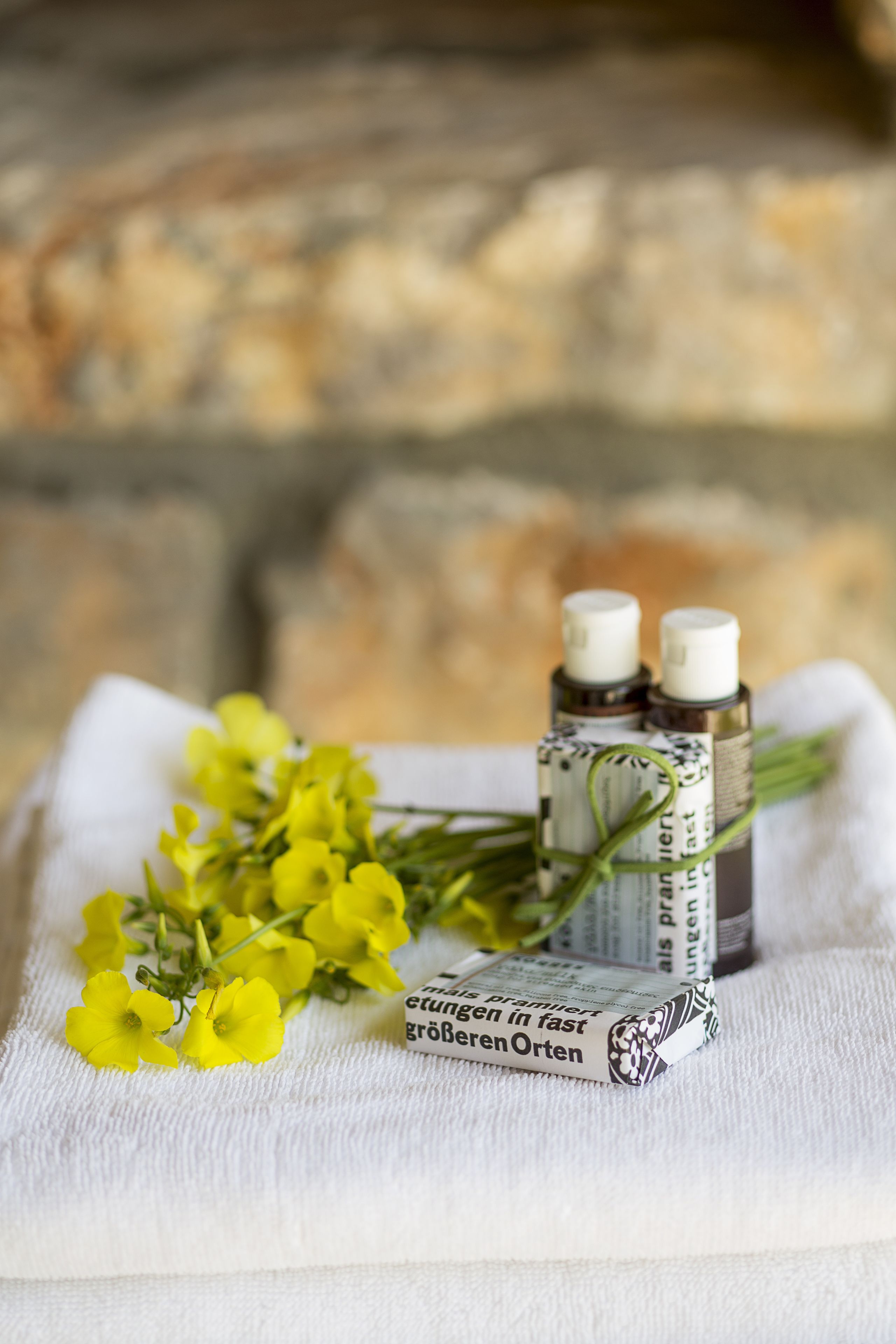 Ein weißes Handtuch mit zwei kleinen Flaschen und gelben Blumen.