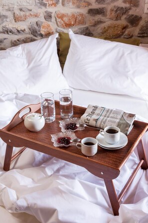 A wooden tray with a newspaper, a teapot, glasses of water, and cups of coffee on a bed with white sheets and pillows. - Agroktima (South Kynouria)