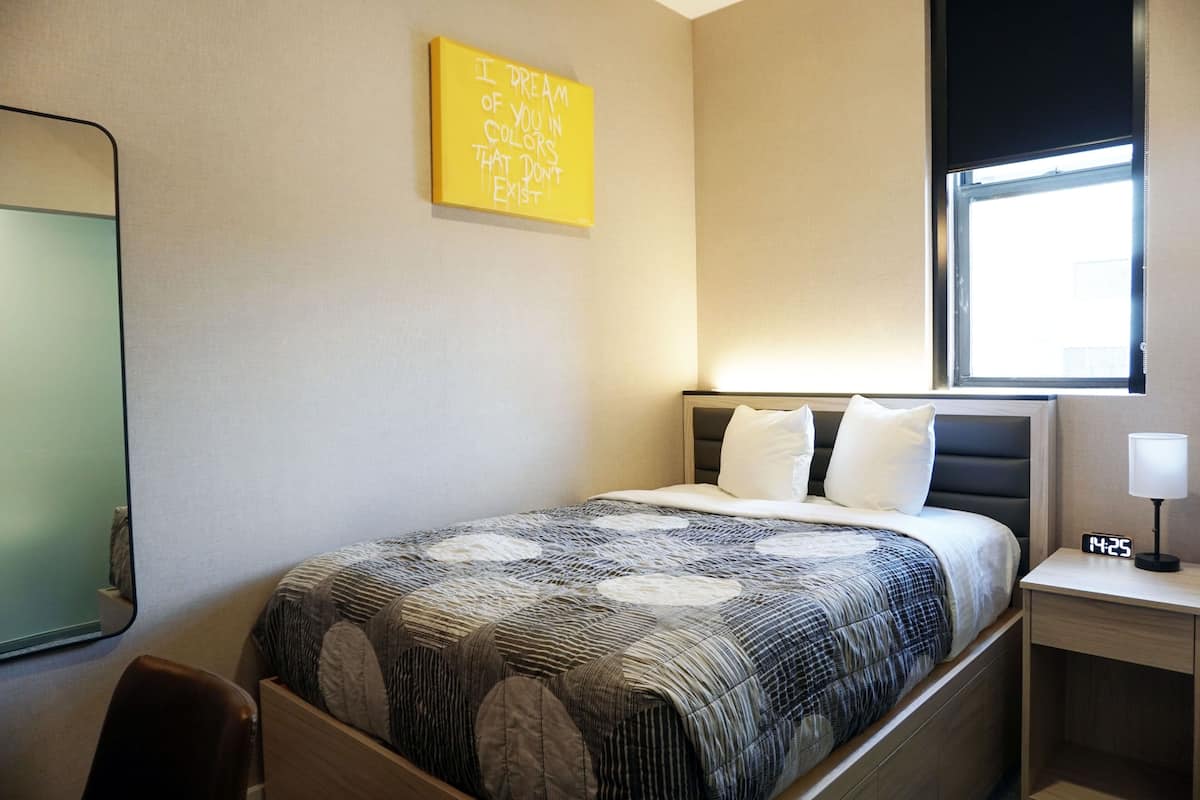 A neatly arranged hotel room with a bed, bedside table, and a window.