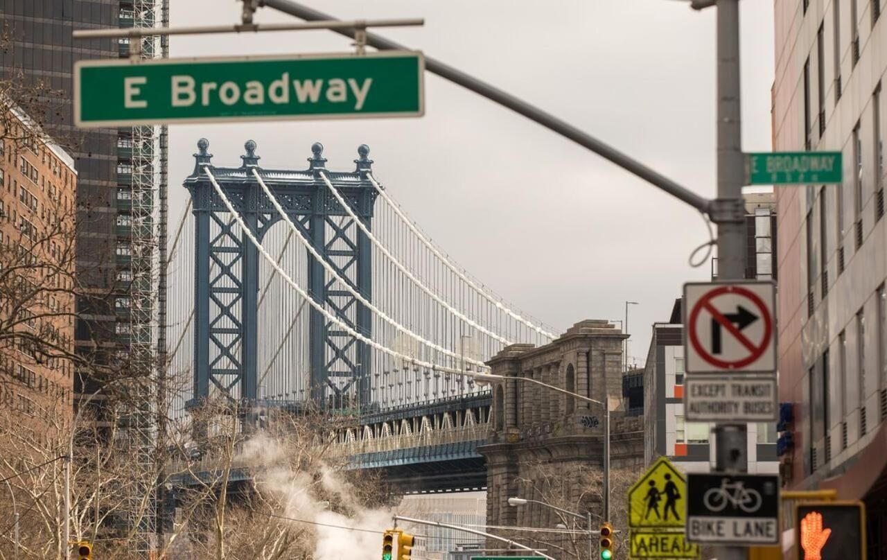 Una señal de calle para E Broadway, un puente y señales de tráfico, incluyendo una señal de prohibido giro a la derecha y una señal de carril bici.