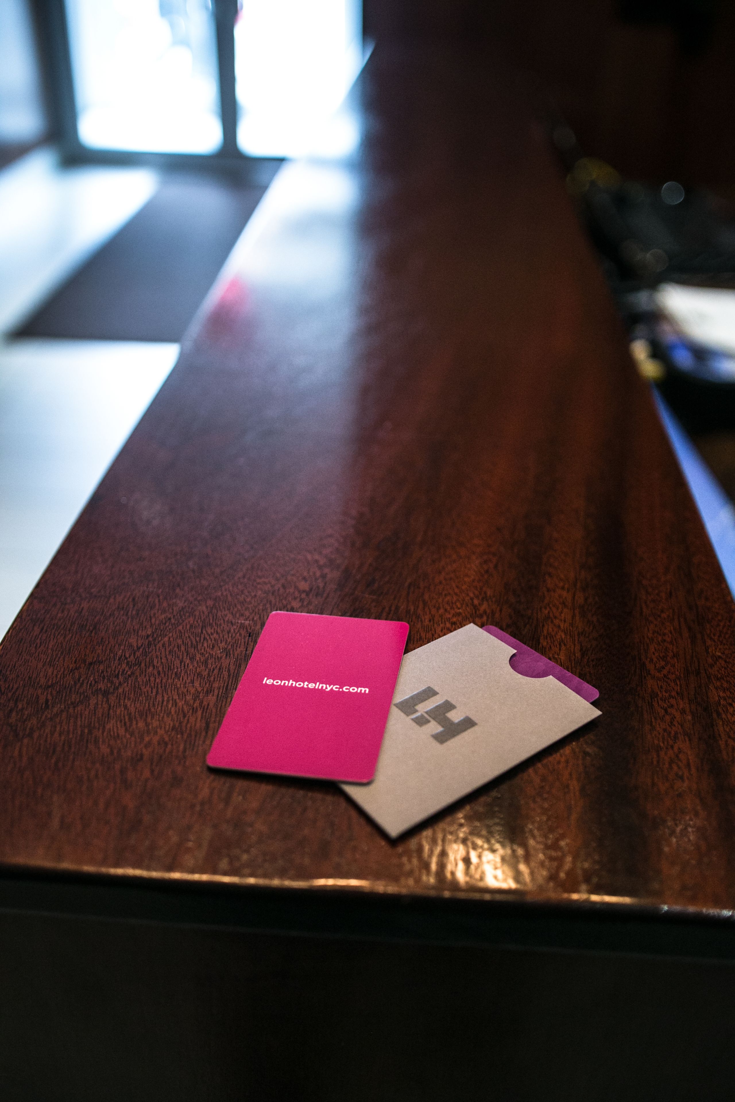 A wooden reception desk with a pink card and a beige card with a purple corner.