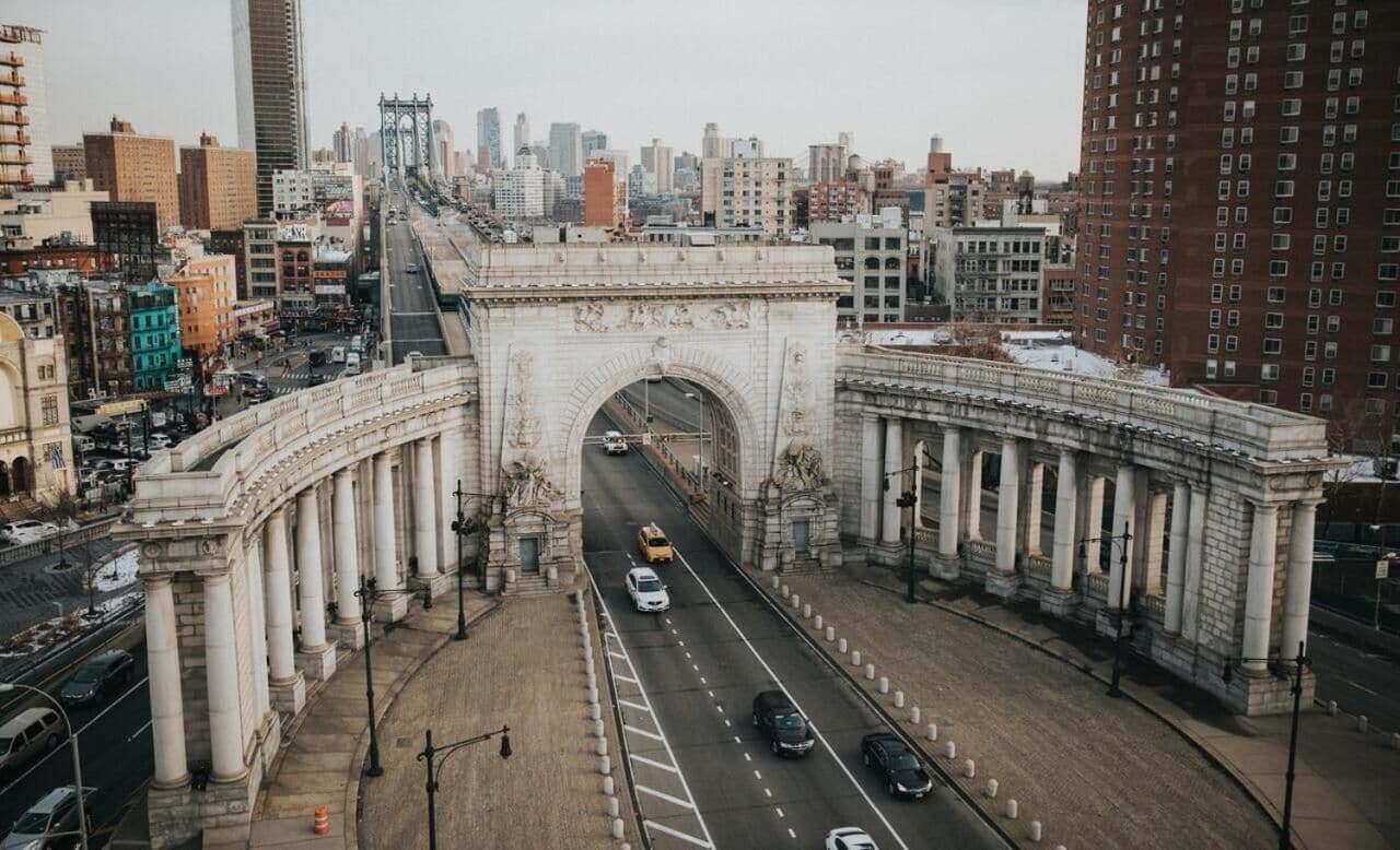 A cityscape with a prominent arch bridge and a busy road.