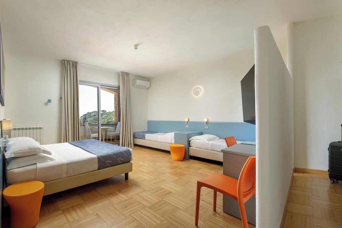 A hotel room with a bed, a desk, a chair, and a suitcase.
