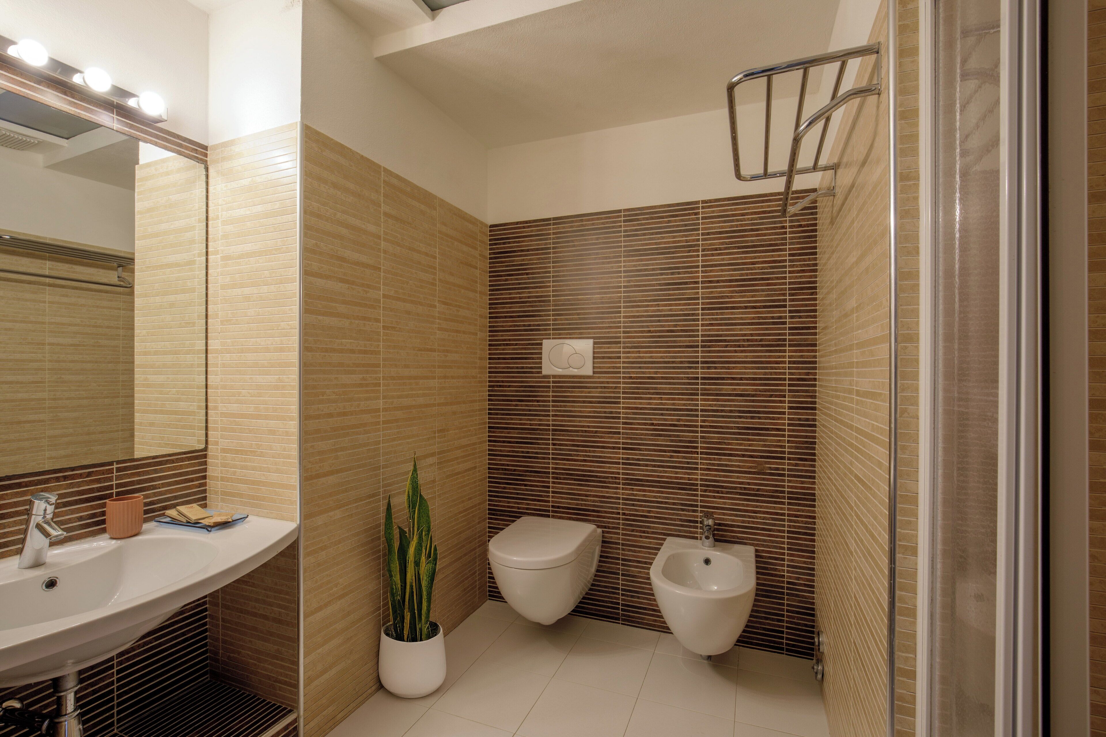 A modern bathroom with a sink, toilet, bidet, and a shower area.