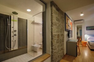 Un baño moderno con ducha de vidrio, un bidé y un lavabo pequeño.