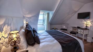 A modern bedroom with a large bed, a desk, and a TV.