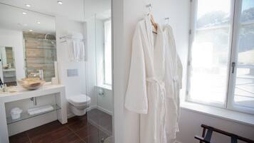 A modern bathroom with a glass shower enclosure, a white sink with a bowl, and a large mirror.