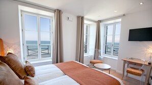Quarto de hotel com uma cama grande, uma escrivaninha, uma cadeira e uma televisão.