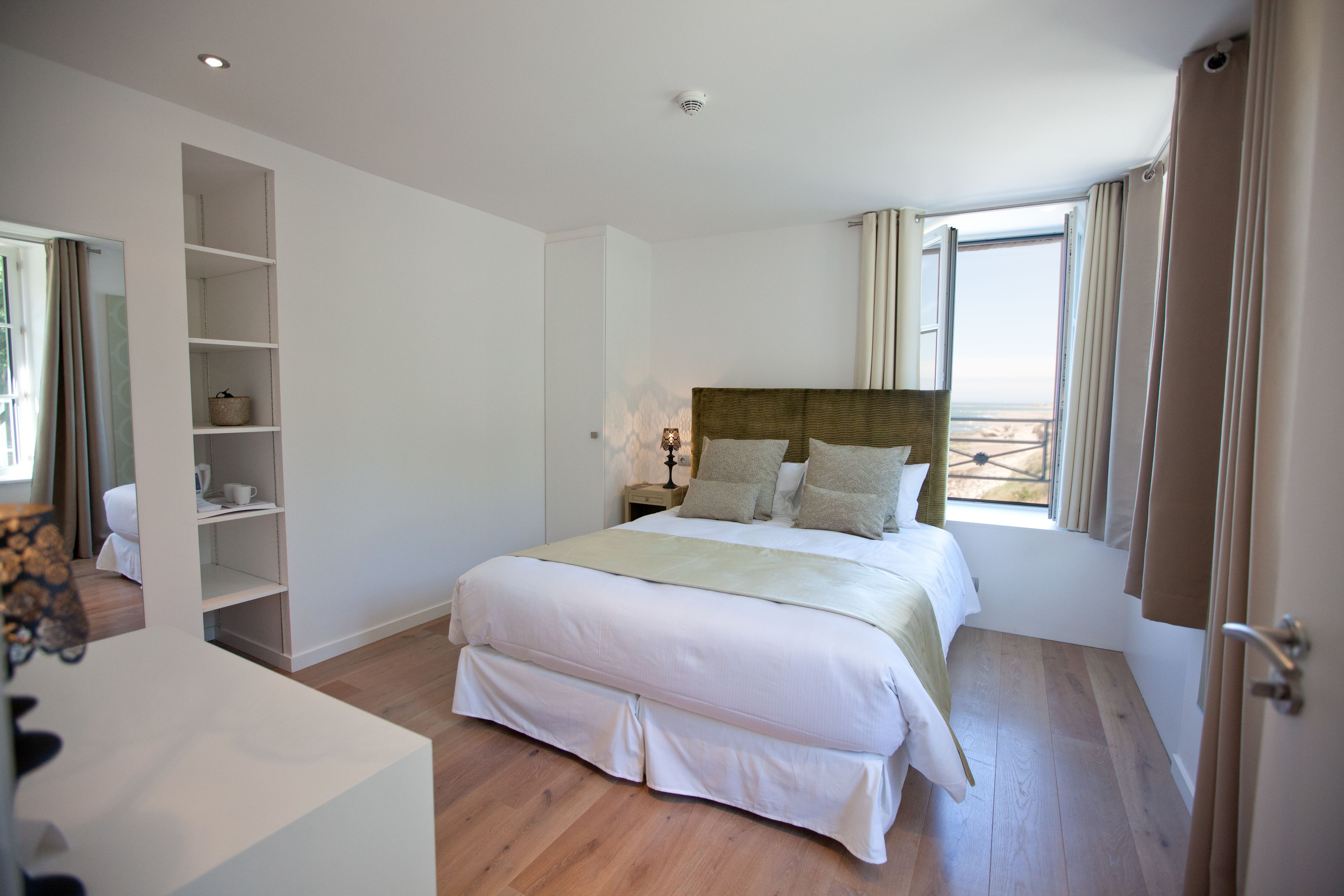 Ein Schlafzimmer mit einem großen Bett, einem Kleiderschrank und einem Fenster mit Vorhängen.