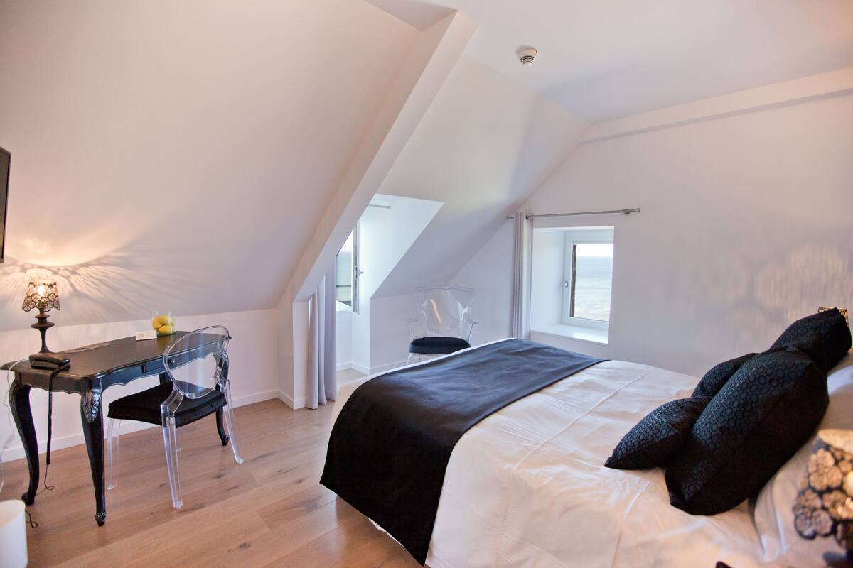 A bedroom with a bed, a desk, and a chair.