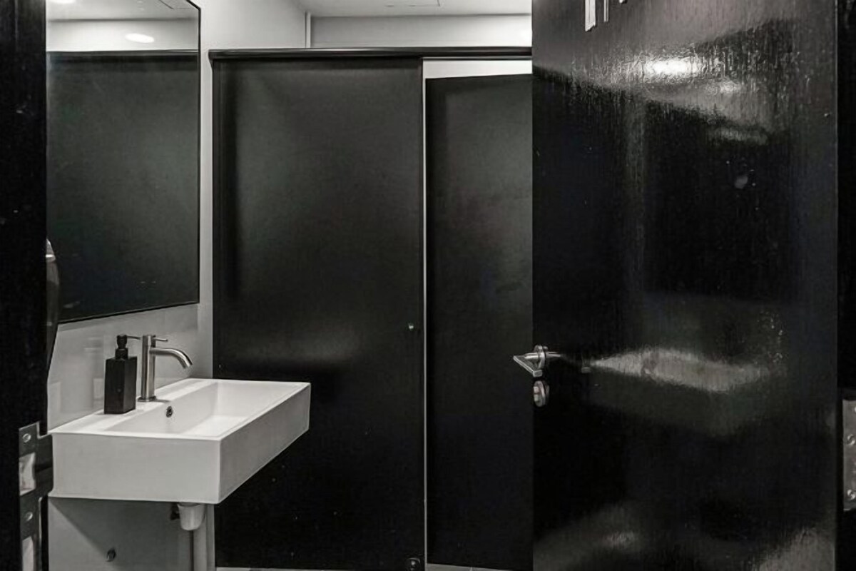 A bathroom with a white sink, a mirror, and a black door.