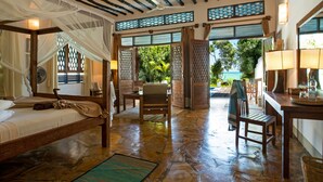 Una habitación con cama con dosel, un rincón de estar con mesa y sillas, y vistas al exterior.