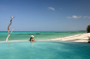 Una piscina al aire libre, sombrillas, sillones reclinables de piscina